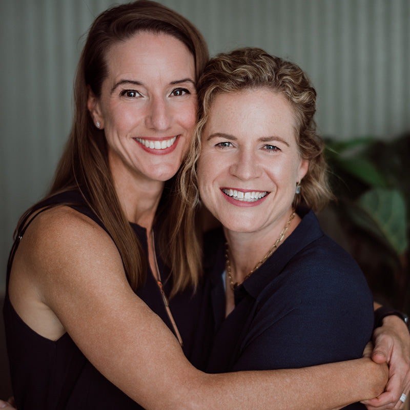 Dr Kate Kelso and WSD Business Manager Jess Rankin hugging and smiling in front of a neutral background