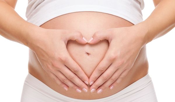 Pregnant belly with hands forming a heart shape on a white background